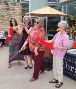 Photo of four women cutting a red ribbon in the library courtyard.